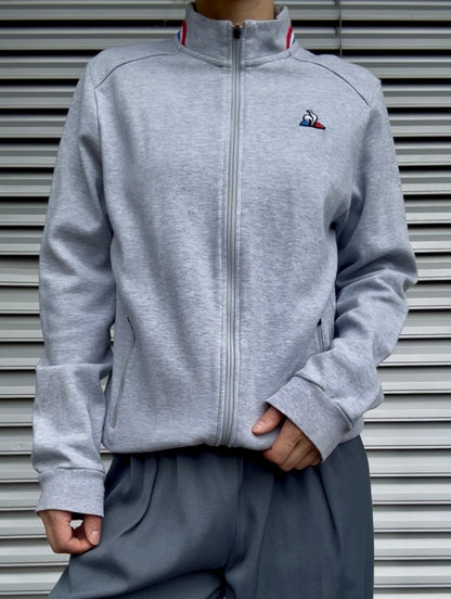 Model wears Secondhand grey cotton Le Coq Sportif Zip-Up Jacket 